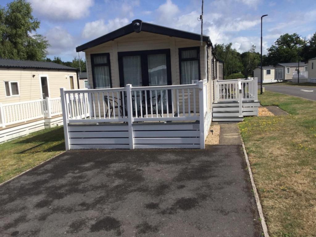 a small house with a white fence and a porch at Poppy 57, Oakdene Forest Park in Bournemouth
