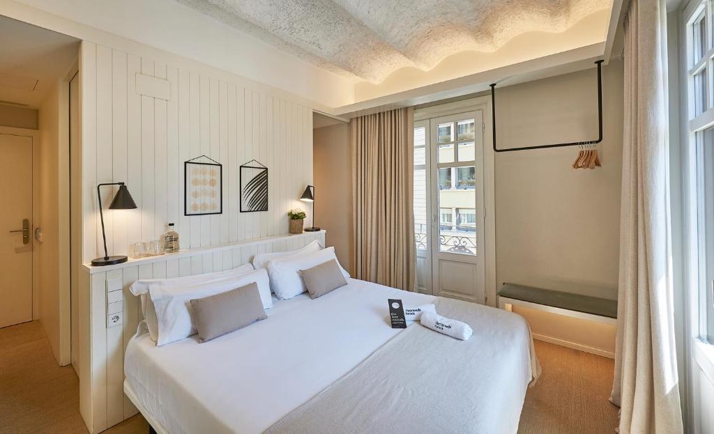 1 dormitorio con 1 cama blanca grande y ventana en The Moods Catedral Hostal Boutique, en Barcelona