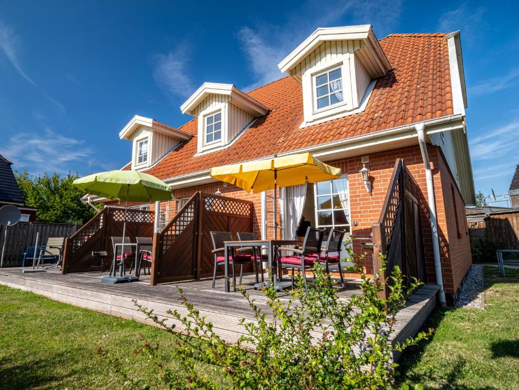 a house with a deck with tables and umbrellas at Residenz "Zu den 3 Tannen" 4 in Zingst