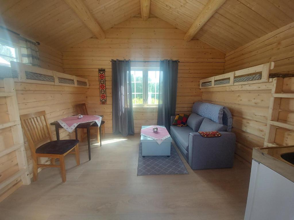 uma sala de estar de um chalé de madeira com um sofá e uma mesa em small camping cabbin with bathroom near by em Hattfjelldal