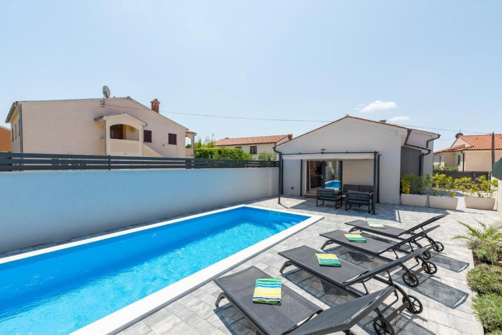 a swimming pool with chaise lounge chairs next to a house at Villa Edera in Bale