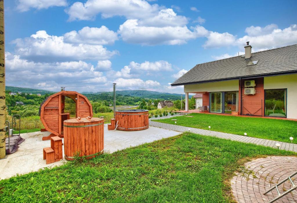 una casa con dos barriles de madera en el patio en ArPioNa dom nad jeziorem z jacuzzi, sauną i placem zabaw, en Dąbrówka