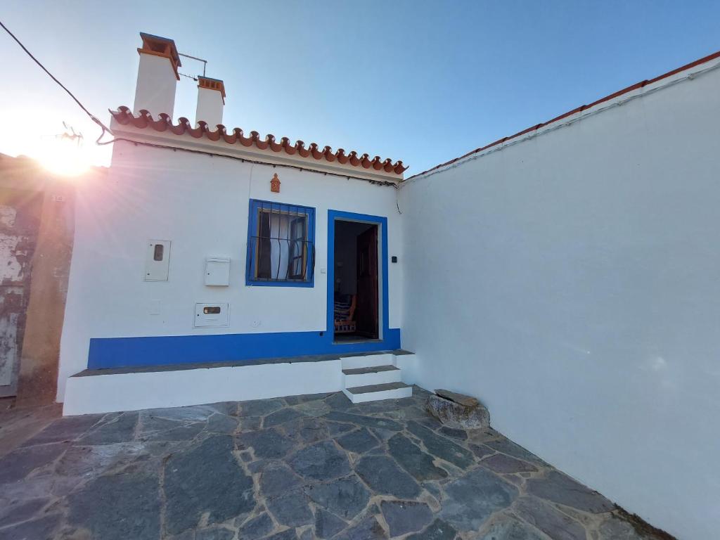 un edificio blanco con una puerta azul y una ventana en Janelas de Monsaraz en Telheiro