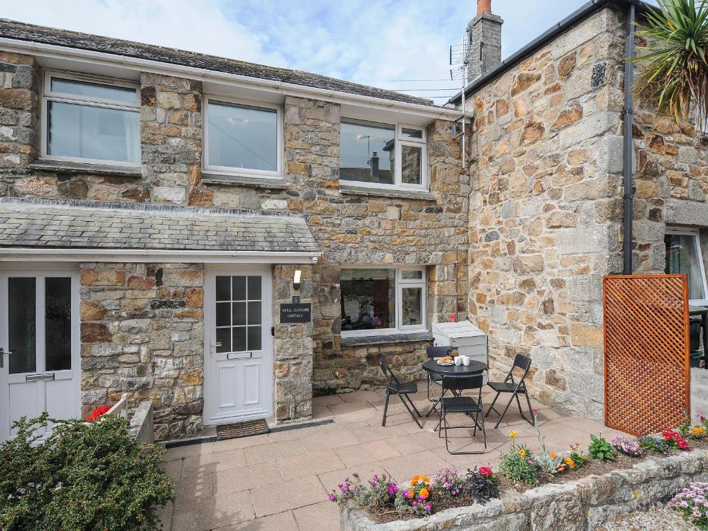 a stone house with a patio in front of it at Wheal Charlotte Cottage in Penzance