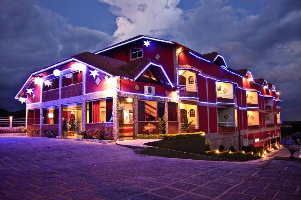 a house lit up at night with lights at Hotel do Papai Noel in Penedo