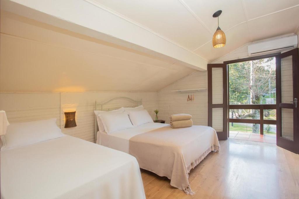 two white beds in a room with a window at Casa no Campo Caminho do Salto in Farroupilha