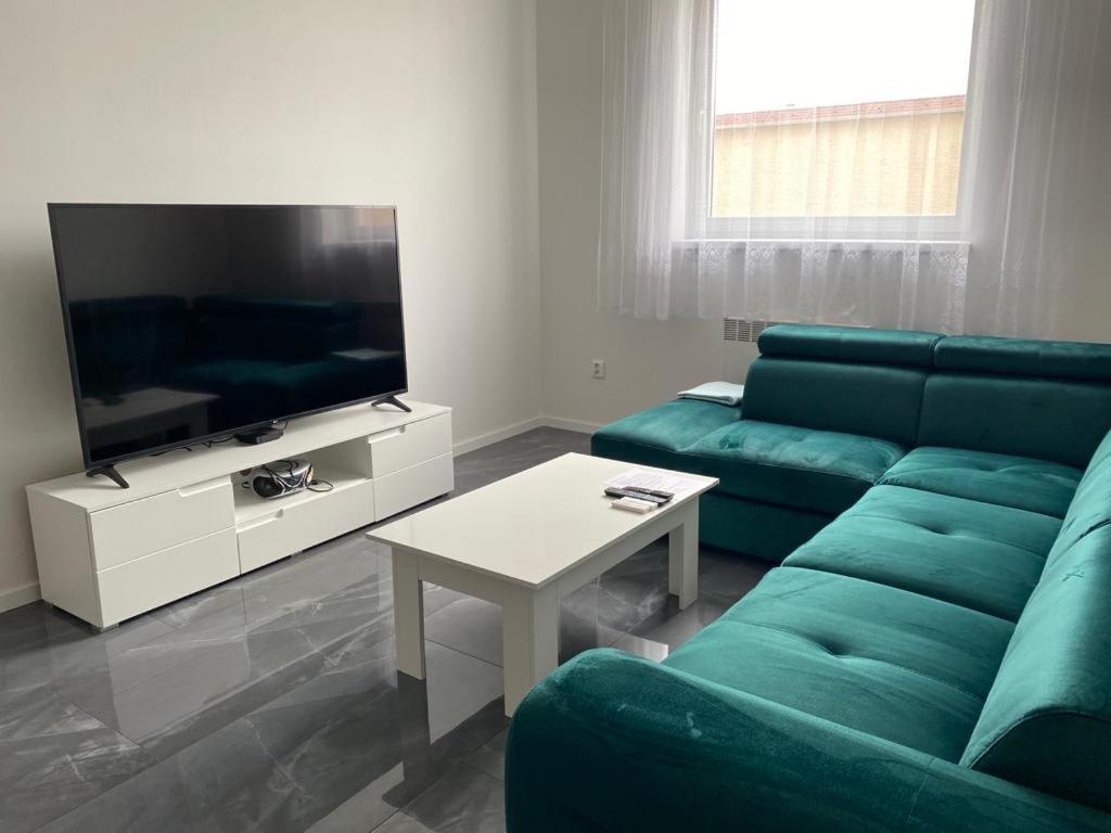 sala de estar con sofá azul y TV en Bezbariérový apartmán Lodenica - v tesnej blízkosti Adelli centra, en Piešťany