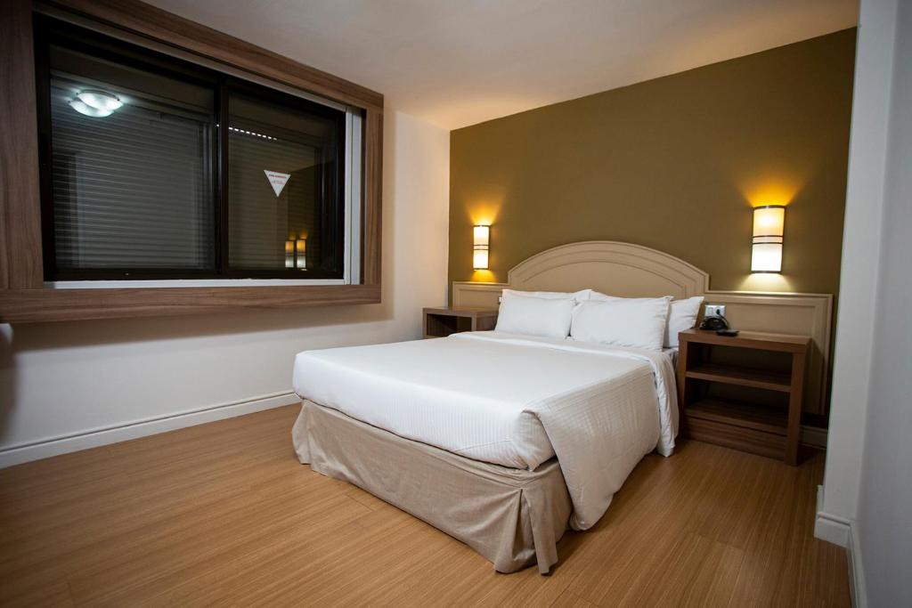ein Schlafzimmer mit einem großen weißen Bett und einem Fenster in der Unterkunft Master Porto Alegre Hotel - Av Carlos Gomes, Proximo Consulado Americano in Porto Alegre