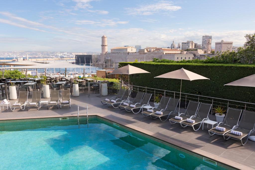 a swimming pool with chairs and umbrellas on a building at Novotel Marseille Vieux Port in Marseille