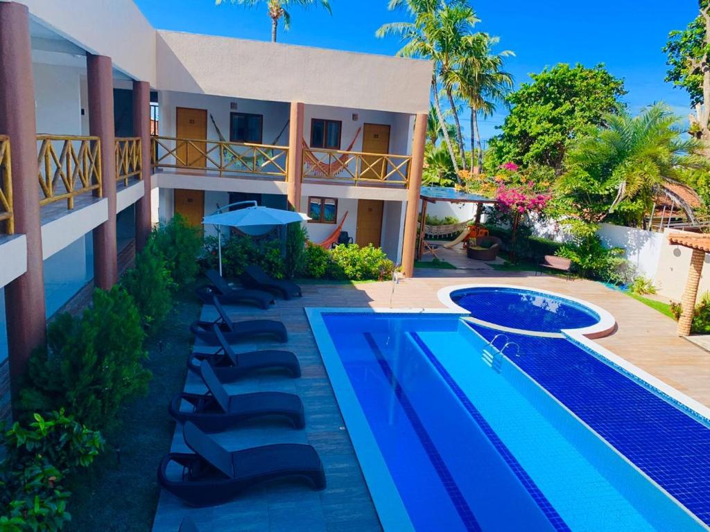 a resort with a swimming pool and lounge chairs at Pousada San Mar in Barra de São Miguel