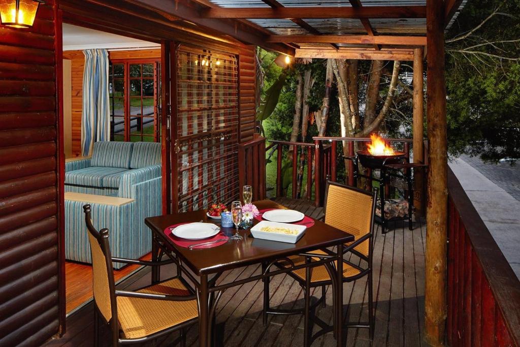 a patio with a table and chairs on a deck at Gooderson Knysna Chalets in Knysna