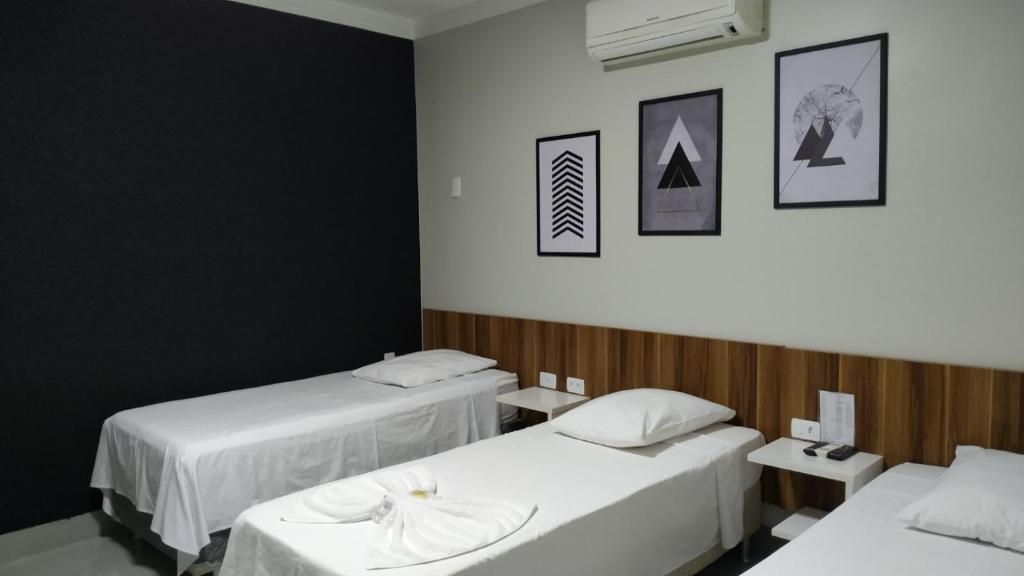 um quarto com duas camas com lençóis brancos em Hotel Barril em Primavera do Leste