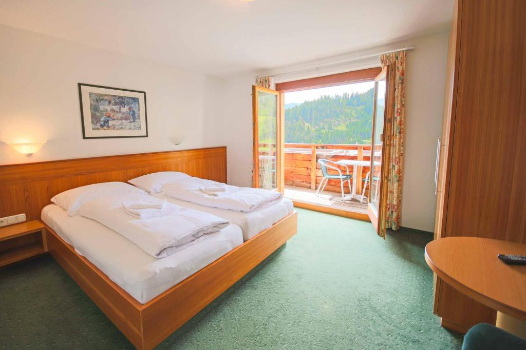 a bedroom with a bed and a balcony with a table at Tirolerhof - Super Sommer Card included in Serfaus