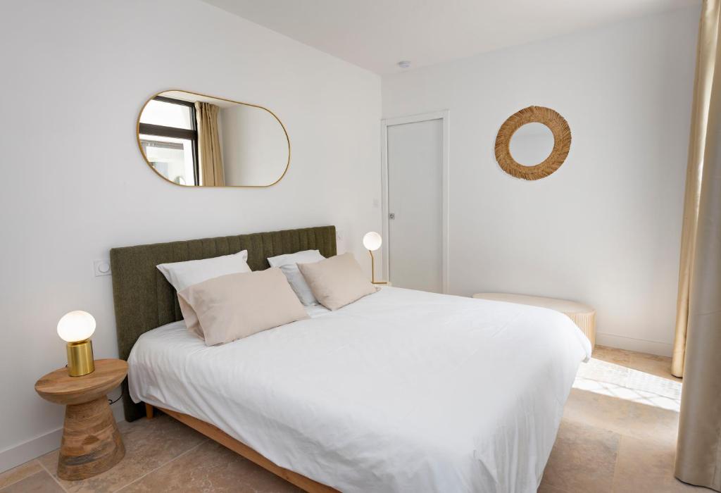 a bedroom with a large white bed with a mirror at Villa Juliane in Cadenet