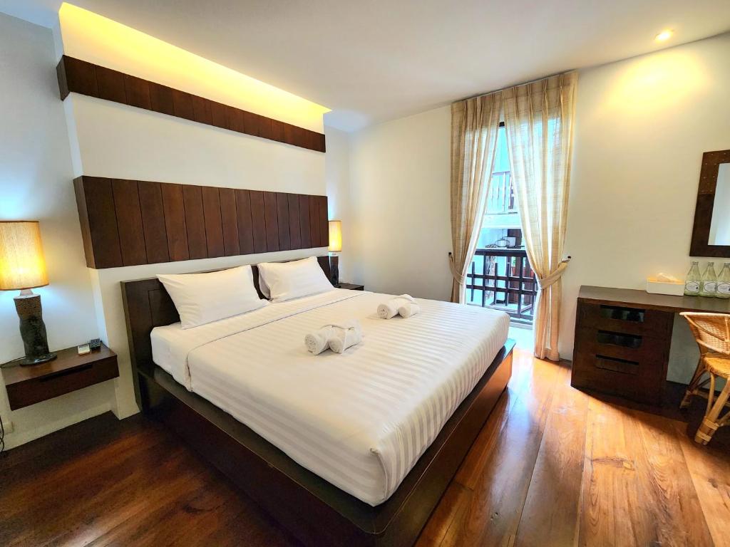 a bedroom with a large bed with two towels on it at The Peaberry Boutique Hotel in Chiang Mai