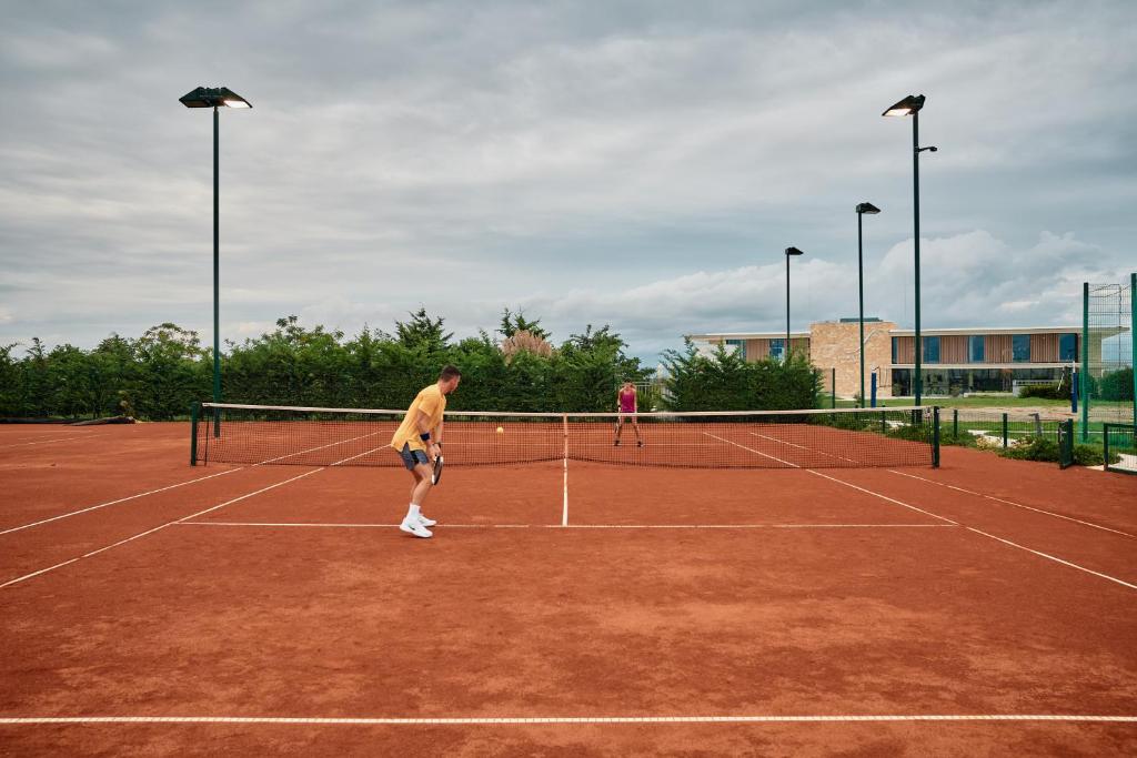 two people playing tennis on a tennis court at Falkensteiner Family Hotel Diadora in Zadar