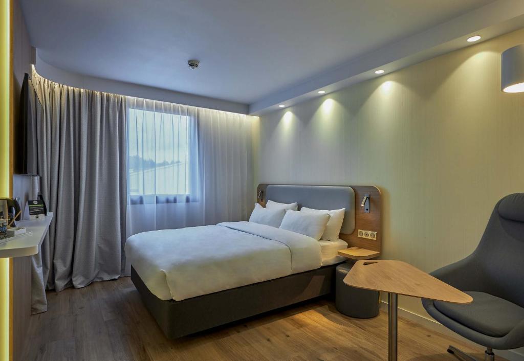 ドーヴィルにあるB&B HOTEL Deauville-Touquesのベッドと椅子付きのホテルルーム