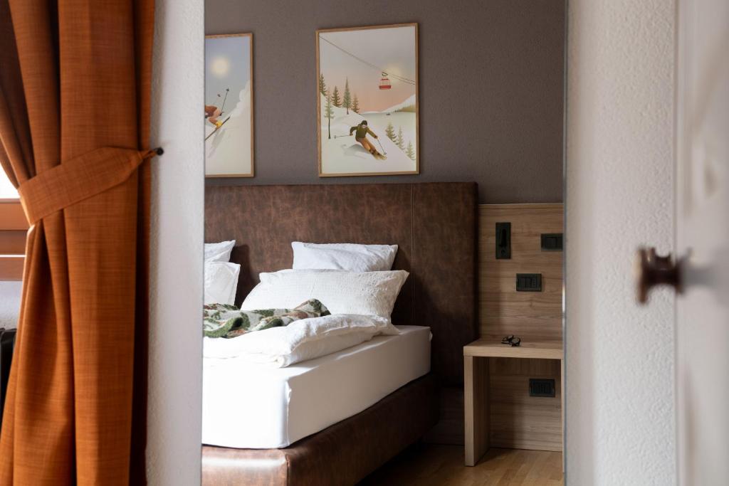 una camera da letto con letto, lenzuola e cuscini bianchi di Chalet Vedig a Santa Caterina Valfurva