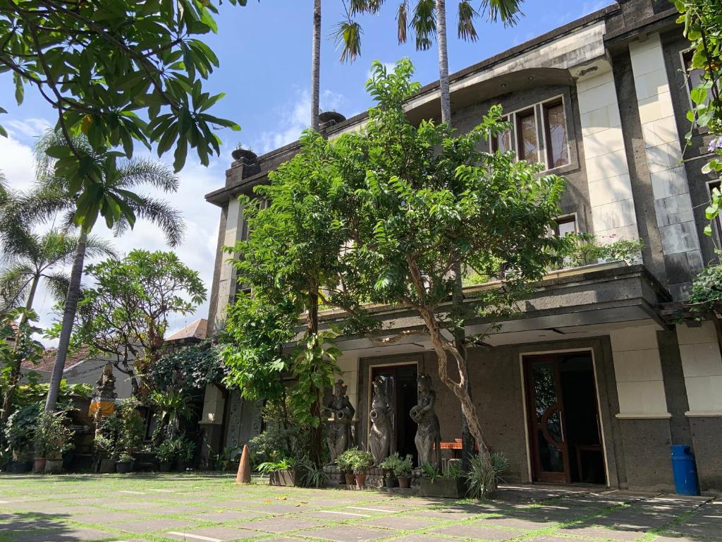 un edificio con un árbol delante de él en Nirwana Suites, en Denpasar