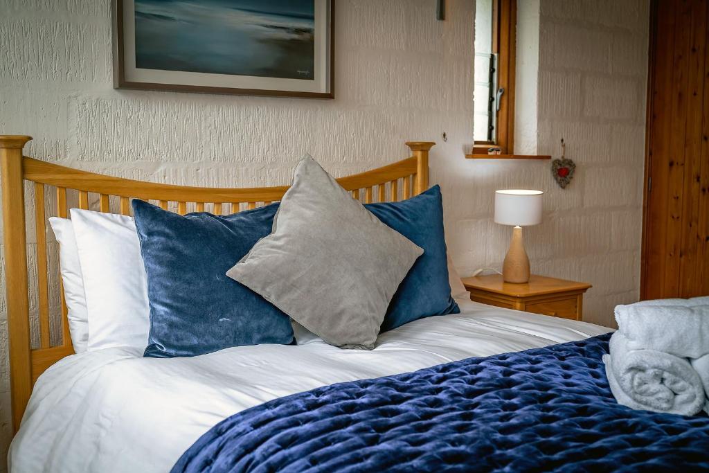 een slaapkamer met een bed met blauwe en witte kussens bij Kirkstone Lodge in Insh