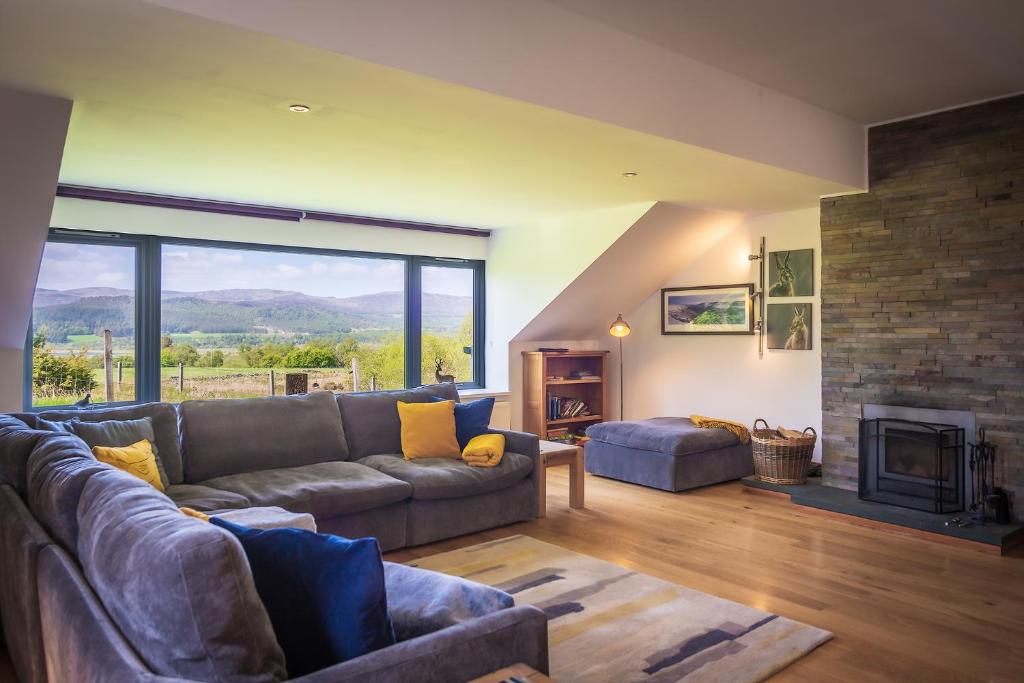 a living room with a couch and a fireplace at Kirkstone Lodge in Insh