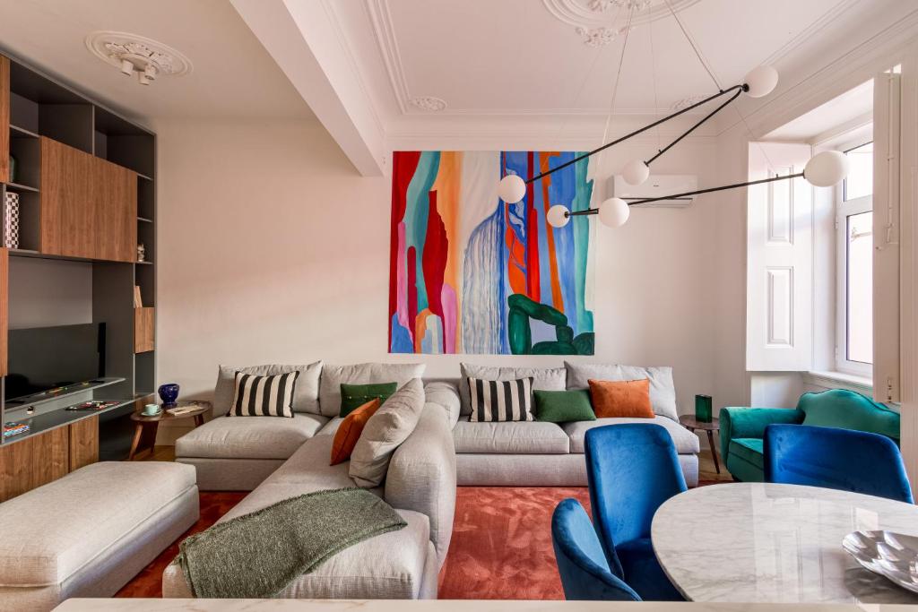 uma sala de estar com um sofá e cadeiras e um quadro em JOIVY Exquisite apt with patio in Graça em Lisboa