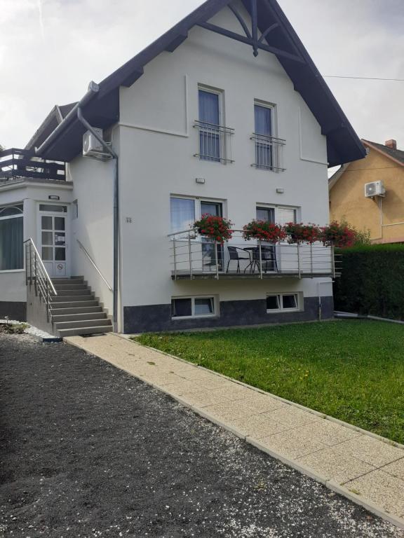 a white house with flowers on the balcony at Family Panzió Zalakaros in Zalakaros