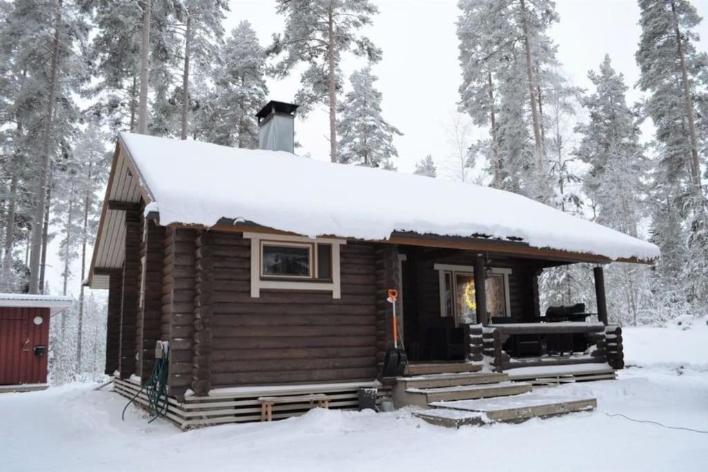 una cabaña de madera con nieve encima en Unique winter holiday in pine forest, en Forssa