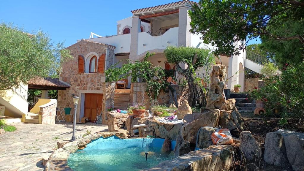 a house with a water fountain in front of a house at I Mari Di Gallura Suites and Rooms in San Teodoro