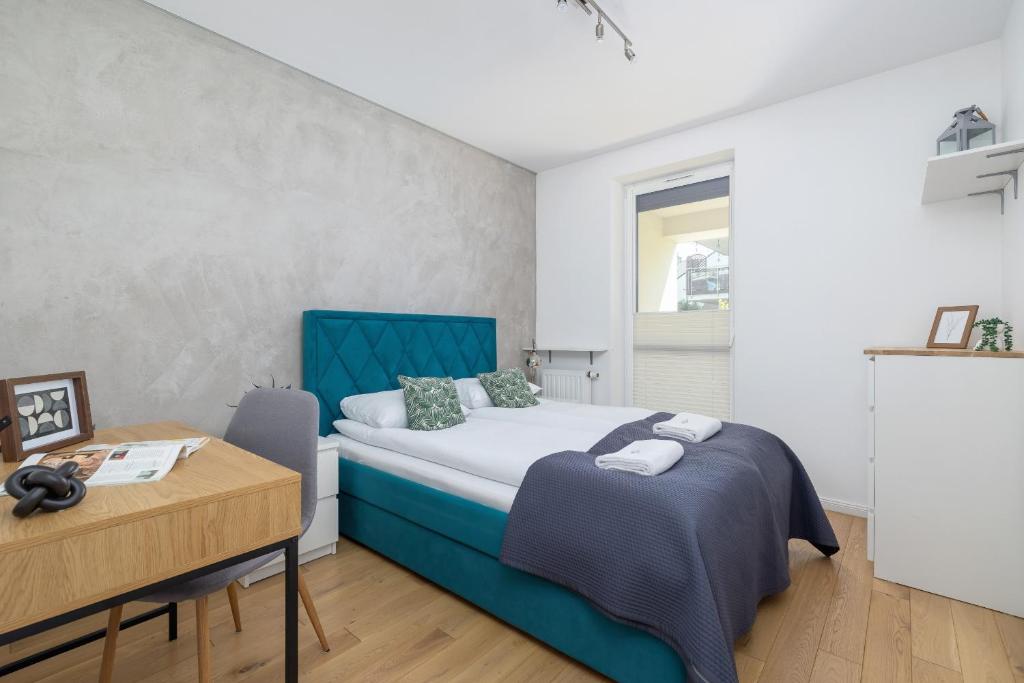 a bedroom with a blue bed and a desk at Osiedle Życzeń Apartment Stawowa Cracow by Renters in Krakow