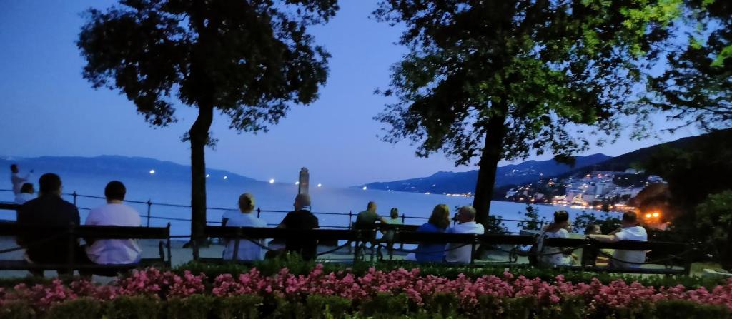 a group of people sitting at a picnic table overlooking the water at Apartments Villa Andreja Opatija in Opatija