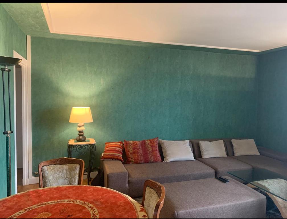 a living room with a couch and a green wall at Chambre dans appartement chez habitants À côté du Lac et du Casino in Épinay-sur-Seine