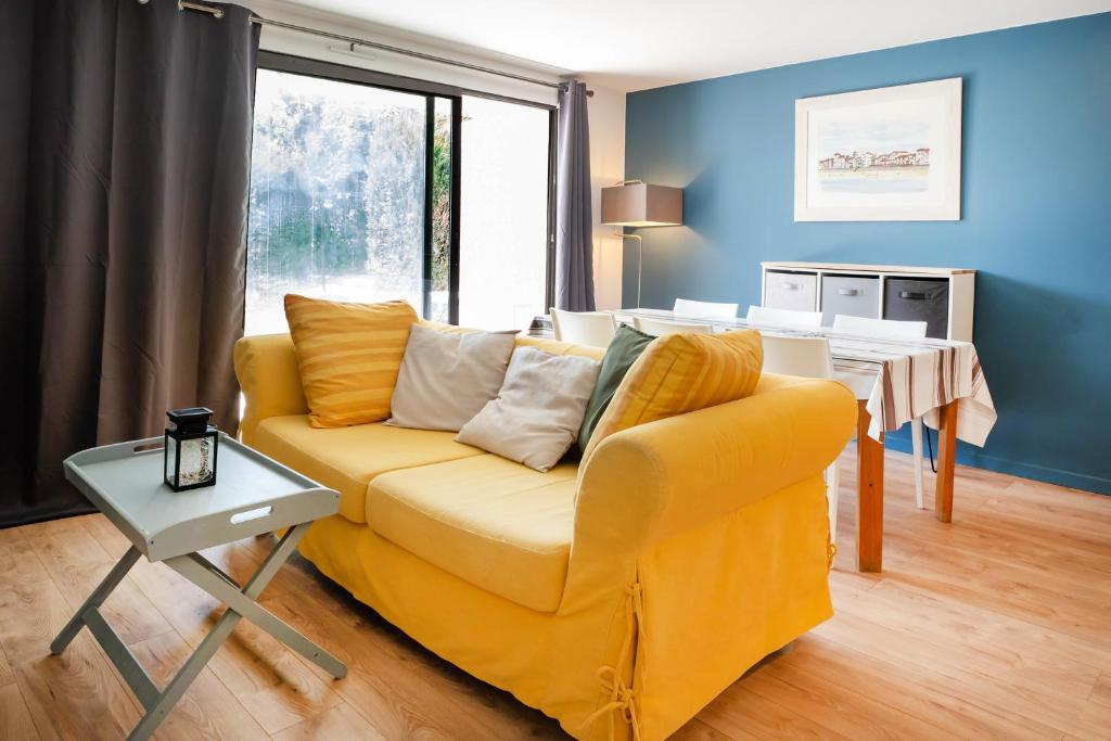 a living room with a yellow couch and a table at Etxe Ttippi in Saint-Jean-de-Luz