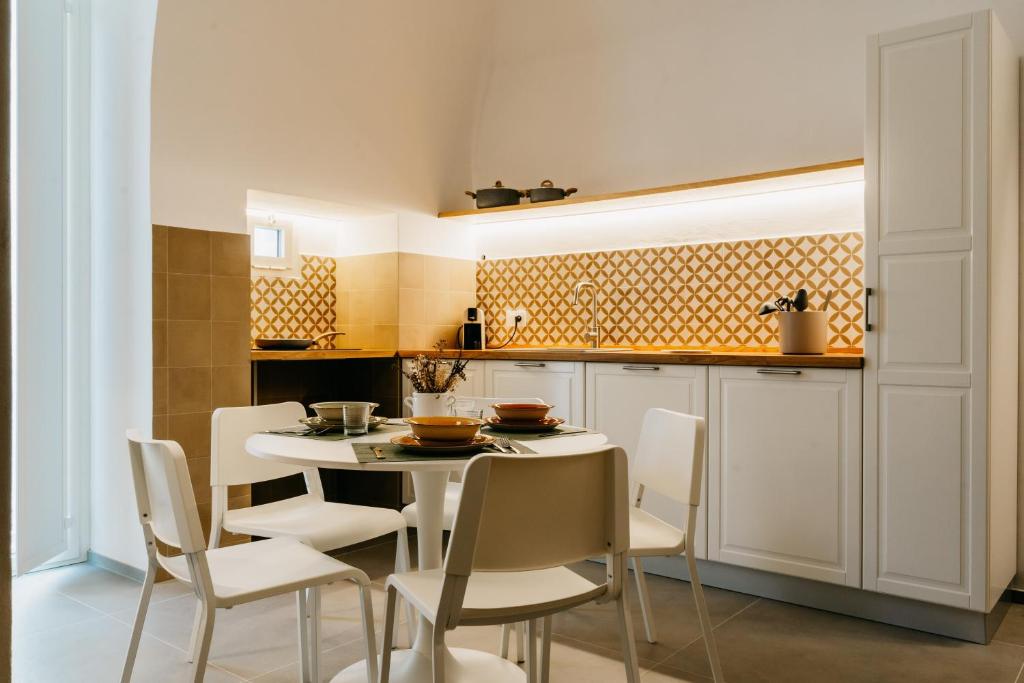 - une cuisine avec une table et des chaises blanches dans l'établissement Dal Monaco - casa vacanze, à Castellana Grotte