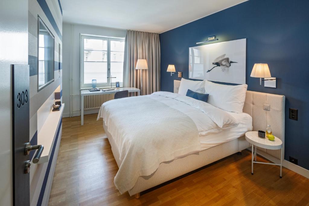 ein Schlafzimmer mit einem großen Bett und einer blauen Wand in der Unterkunft Hotel Seehof in Zürich