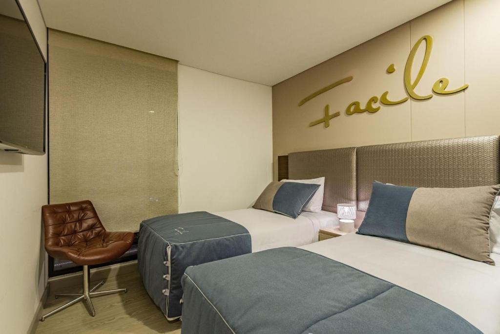 ein Hotelzimmer mit 2 Betten und einem Stuhl in der Unterkunft Apartametos FACILE in Bogotá