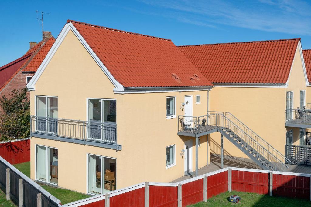 una casa con techos rojos y una valla roja en Skagen Harbour Apartments, en Skagen