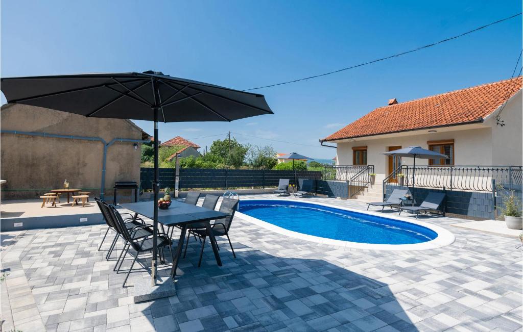 um pátio com uma mesa e um guarda-sol ao lado de uma piscina em Gorgeous Home In Runovici With Kitchen em Runović
