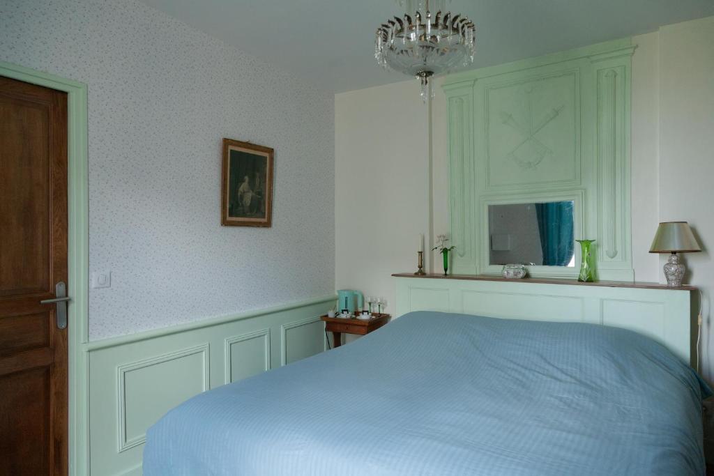 Un dormitorio con una cama azul y una lámpara de araña. en les chambres fleuries, en Saint-Benoît-du-Sault