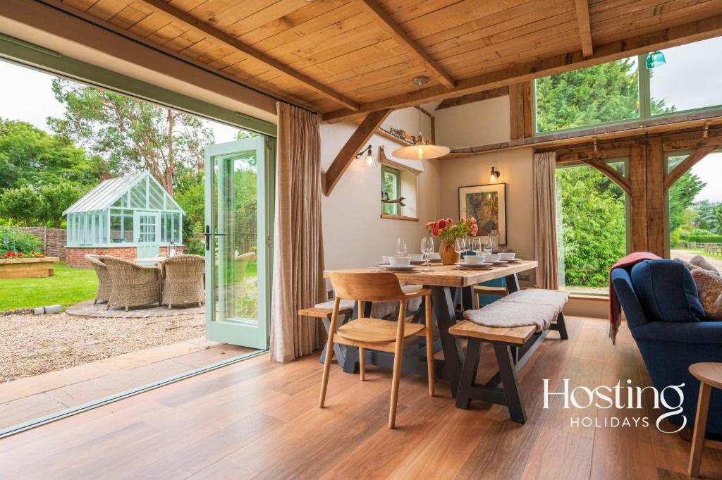 einen Wintergarten mit einem Tisch und Stühlen in einem Haus in der Unterkunft Foxglove Barn - Rurally located 3 bed equestrian paradise in Aylesbury