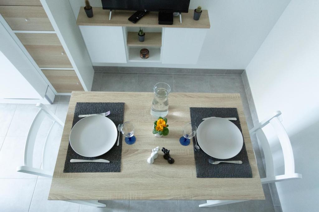 une table avec deux assiettes blanches et des verres dans l'établissement Logement équipé, à Saint-Paul-de-Varax