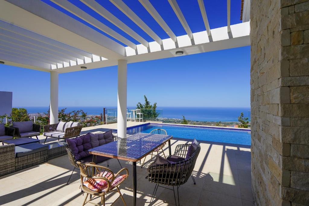 eine Terrasse mit einem Tisch und Stühlen sowie einem Pool in der Unterkunft Resitour - Karina Heights Villas in Tala