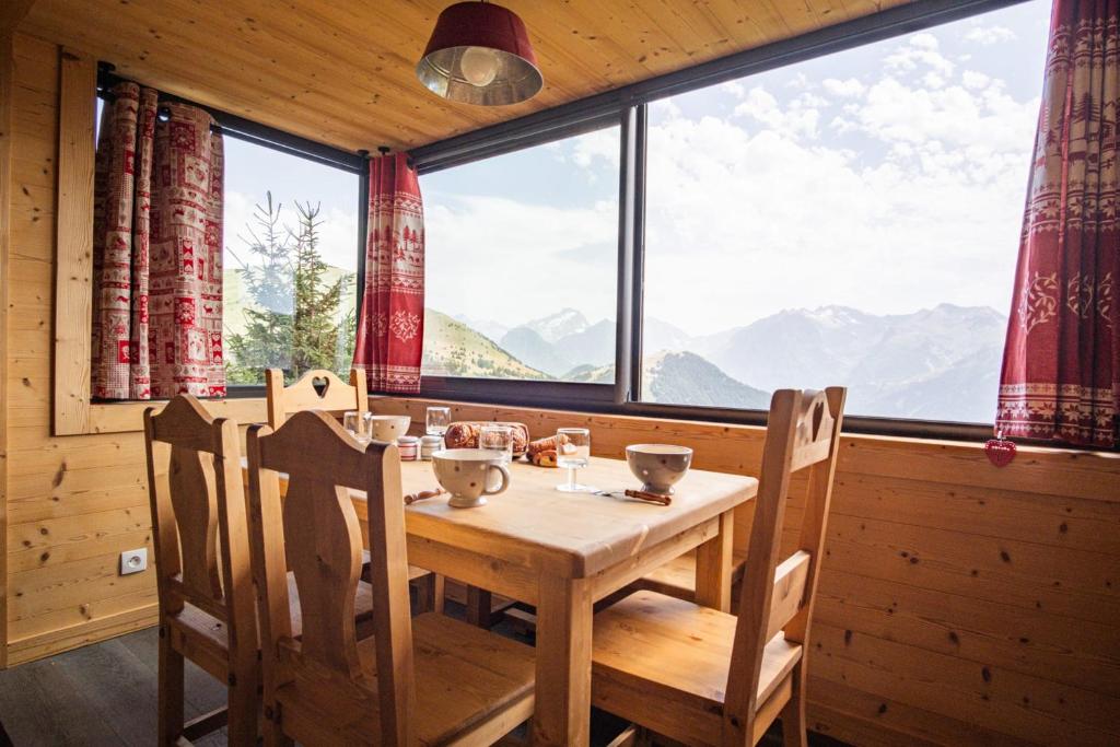 a dining room with a table and chairs and a large window at Apartment with a superb view in l'Alpe d'Huez - Welkeys in LʼHuez