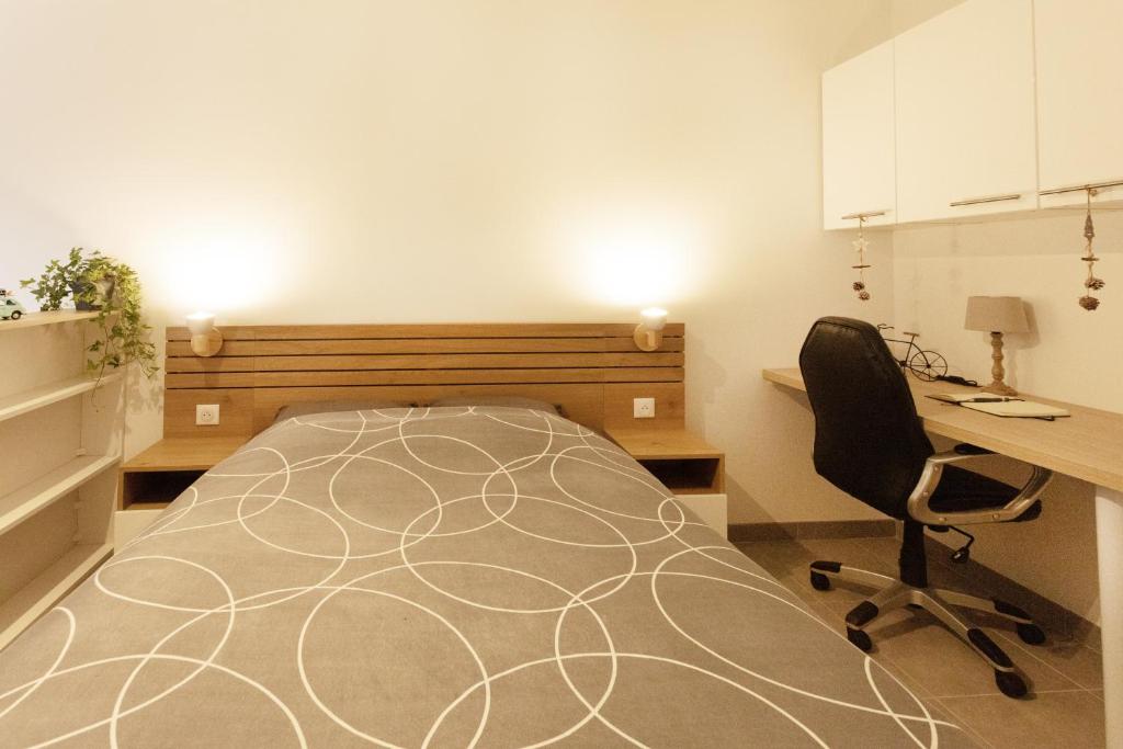 1 dormitorio con cama, escritorio y silla en Logement équipé en Saint-Paul-de-Varax