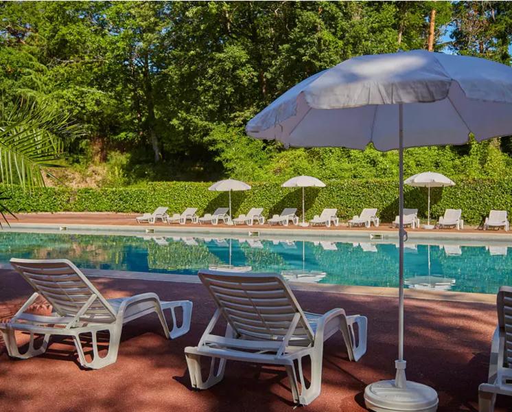 two chairs and an umbrella next to a swimming pool at Camping Parc des Roches-Mobilhome in Saint-Chéron