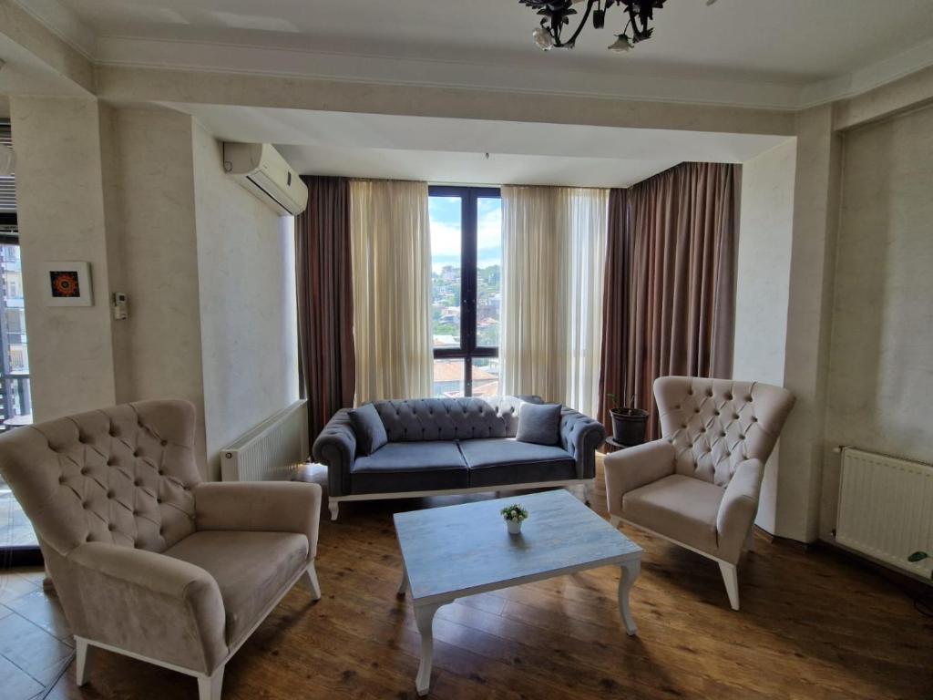 Una sala de estar con un sofá y sillas y una mesa. en 3 Bedroom 2 Bathroom Apartment on Saburtalo Gagarin, en Tiflis