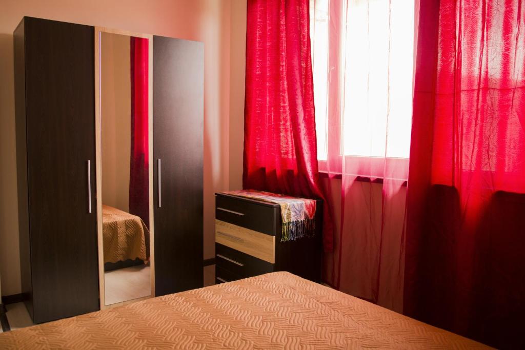een slaapkamer met rode gordijnen, een bed en een raam bij Private Rooms Kranevo in Kranevo