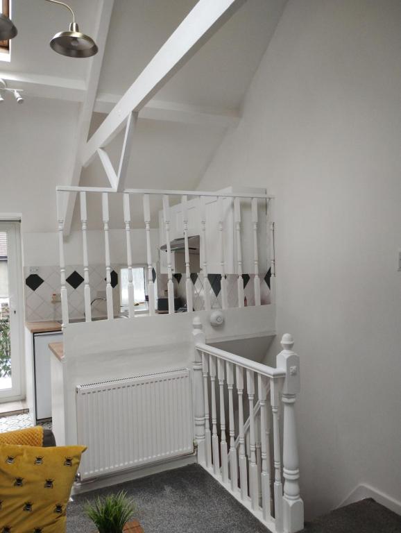 a white staircase in a living room with white railings at Cwtch Cottage in Rhondda
