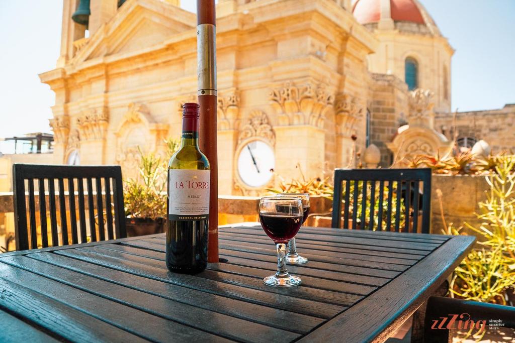 butelka wina na drewnianym stole ze szklanką w obiekcie A pretty apartment in a Gozo village square w mieście Victoria