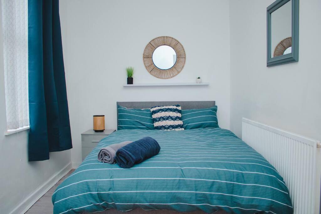 a bed with a blue comforter and a mirror at Nicely made relaxing 4 Bedroom near LFC Stadium in Liverpool